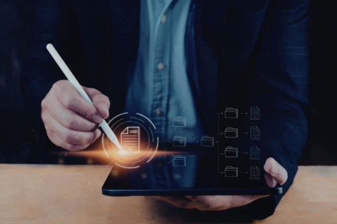 Un homme d'affaires utilise un stylet sur une tablette pour organiser des dossiers numériques flottants, illustrant le processus moderne pour numériser ses documents.