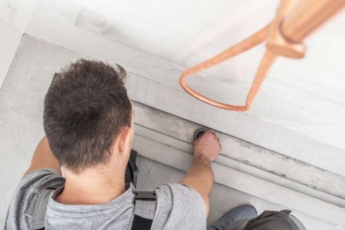Un technicien en train d'entretenir ses canalisations en nettoyant l'évacuation d'une douche à l'italienne.