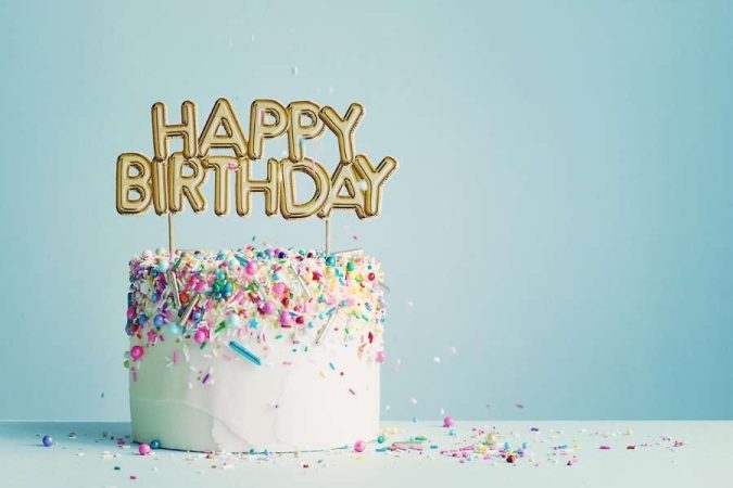Un magnifique gâteau d'anniversaire recouvert de vermicelles colorés avec une décoration dorée pour un anniversaire inoubliable.