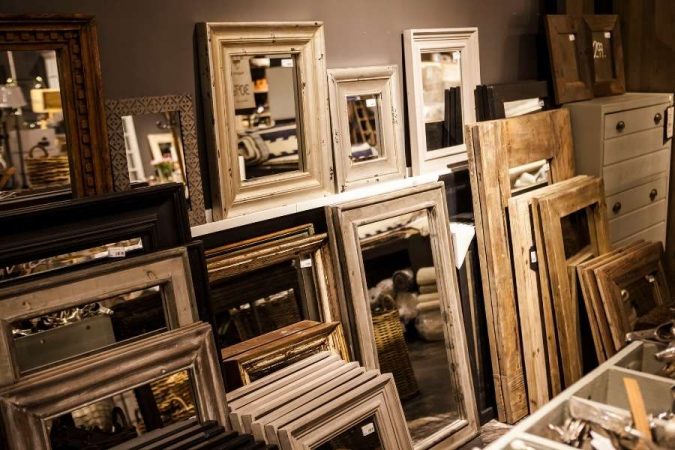 Un grand choix de cadres de miroir en bois exposés dans un magasin de décoration.