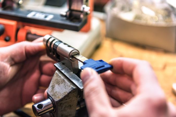 Un serrurier réparant ou ajustant un cylindre qui tourne fou dans un étau d'atelier à l'aide d'une clé.